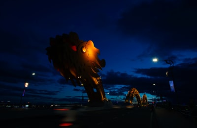 At night, buildings nearby brown dragon sculpture in outdoor
